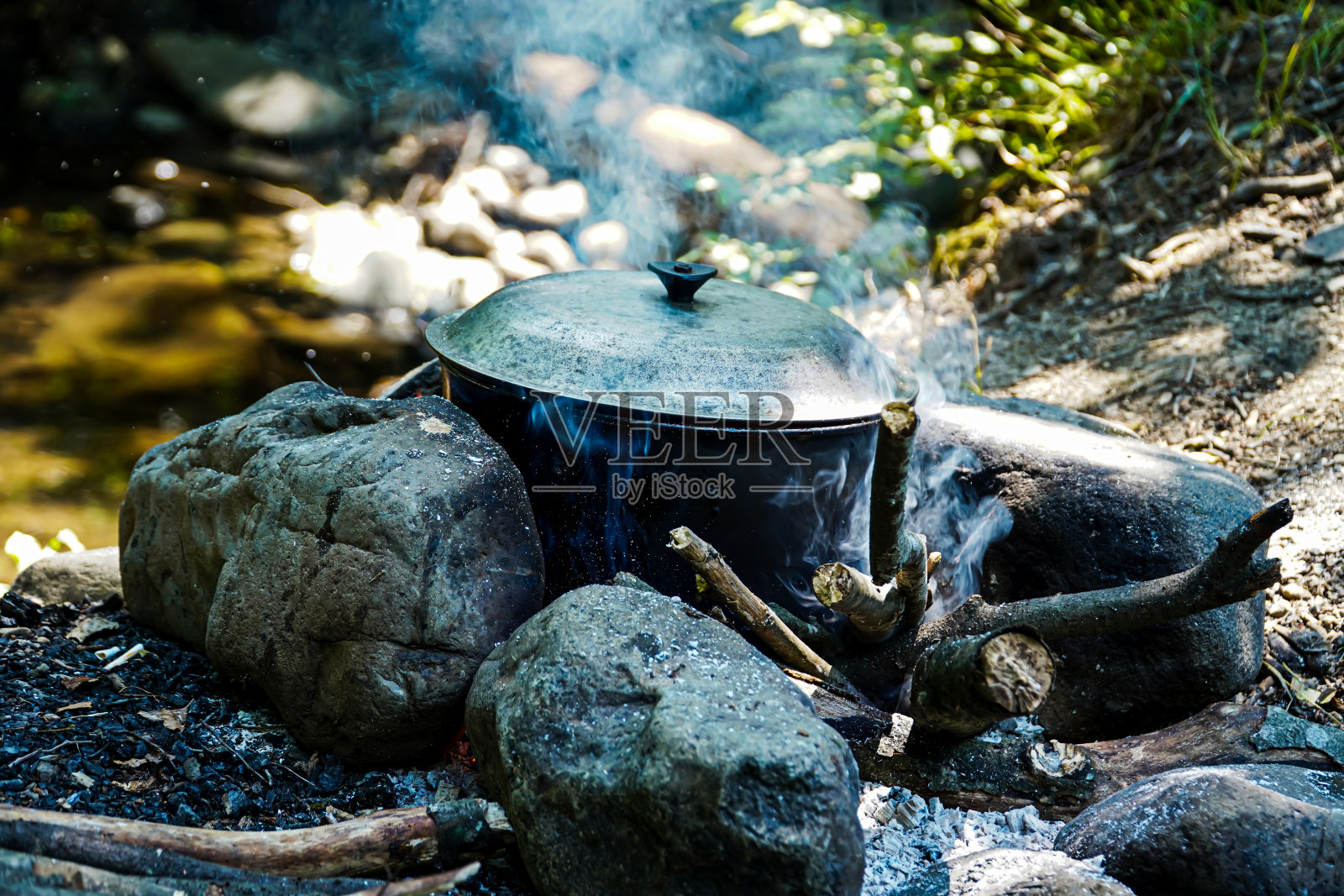 篝火上有水壶,河岸上有锅,树林里有野餐照片摄影图片