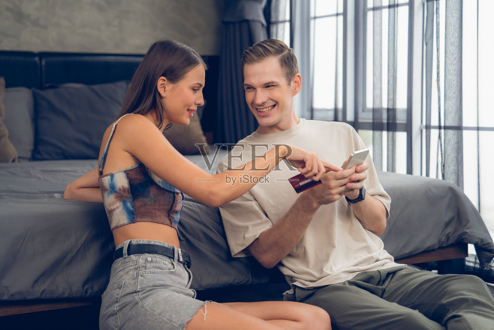 年轻夫妇坐在卧室里使用在线支付应用照片摄影图片