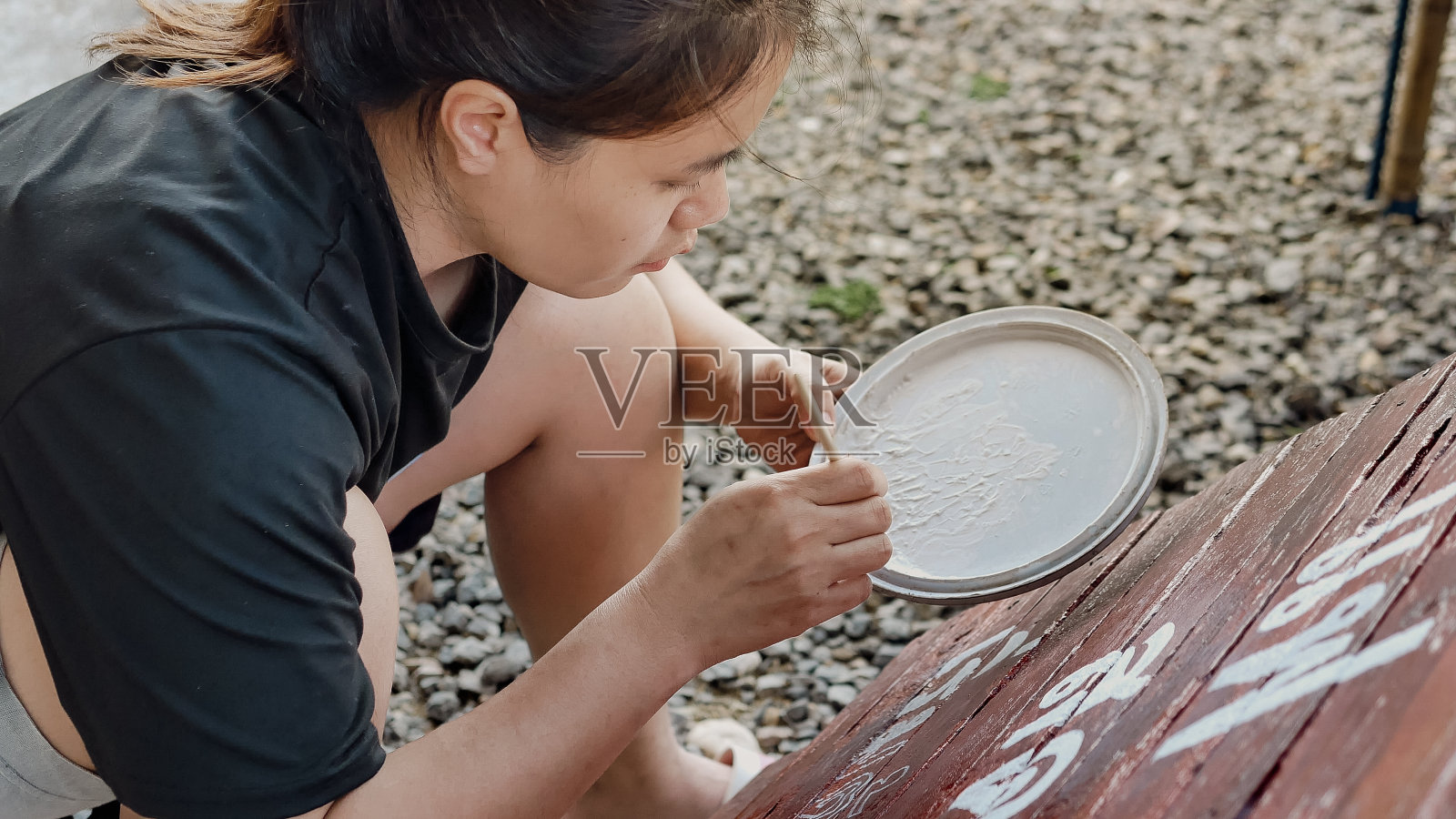 创作艺术的亚洲女画家用画笔在木制咖啡馆招牌上画出字母设计。户外活动,人们做活动。照片摄影图片