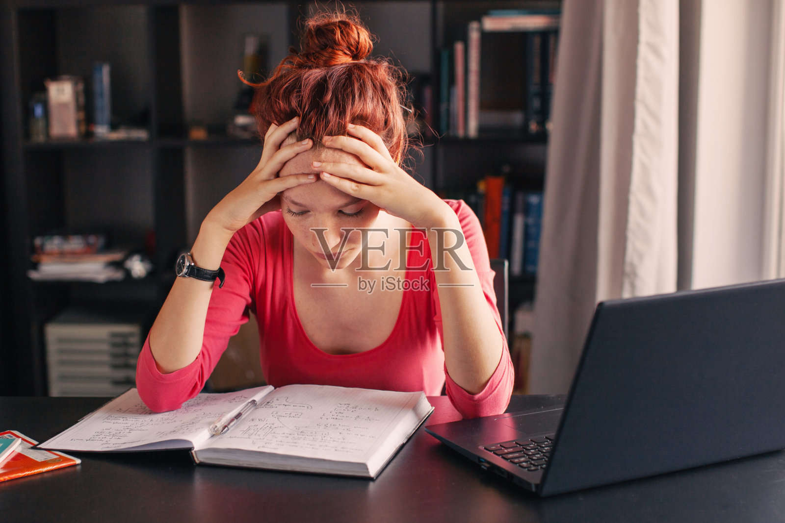 看着笔记本电脑和笔记本的悲伤疲惫的女学生照片摄影图片