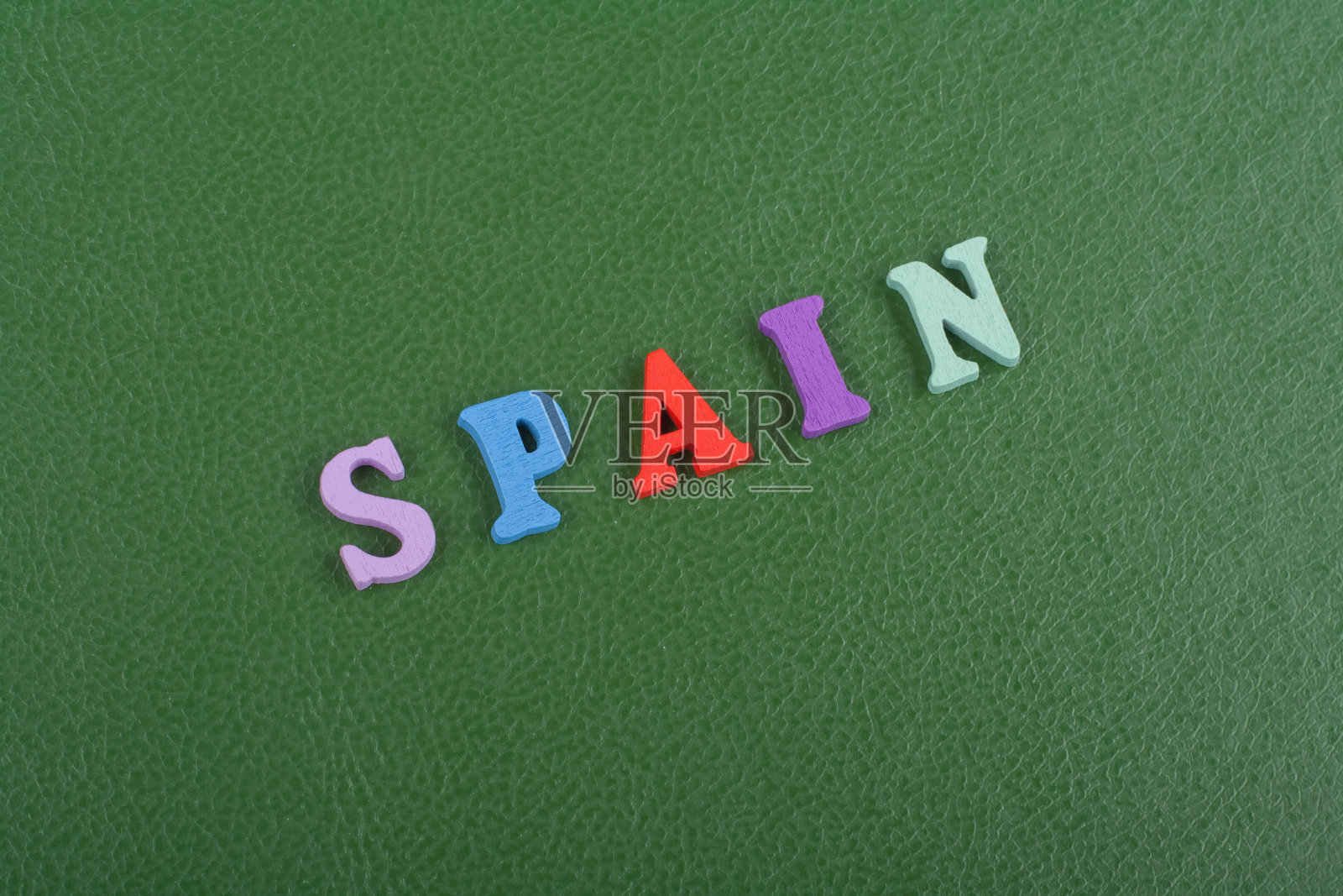 绿色背景上的西班牙语单词由彩色abc字母表块木制字母组成,用于广告文本的复制空间。学习英语的理念。照片摄影图片