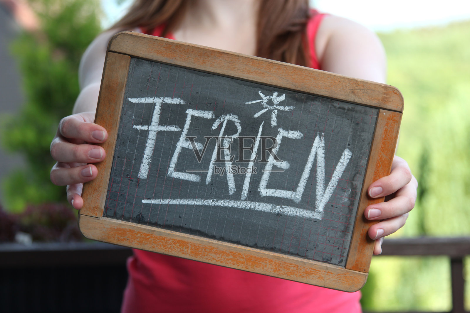 年轻女性用粉笔在石板上书写的假期(德语中的假期)照片摄影图片