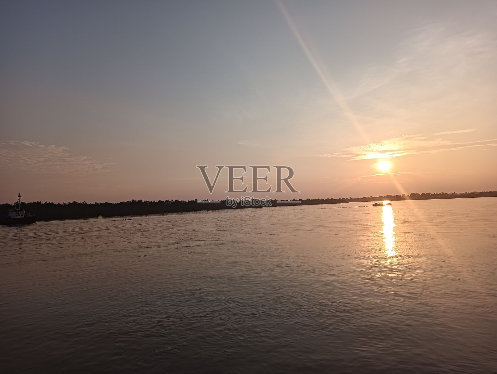 太阳正落在船甲板上的水面上照片摄影图片