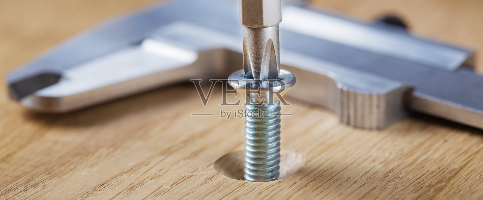 在橡木木板上用螺丝刀拧螺丝照片摄影图片