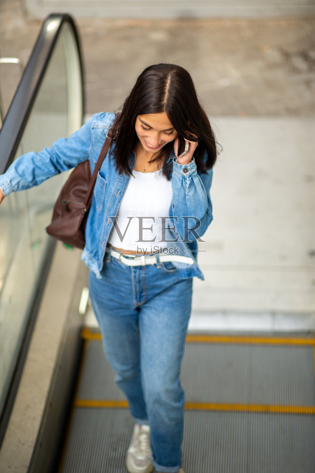 年轻女子在自动扶梯上用手机打电话照片摄影图片