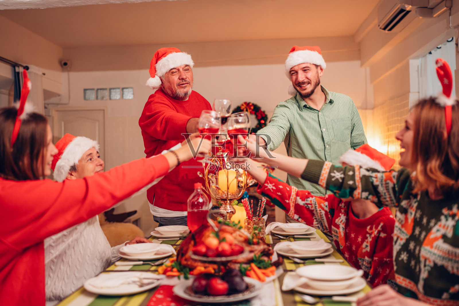 阖家欢乐笑口常开欢度圣诞,举杯共饮美酒。家庭成员在家里享用自制的烤火鸡大餐。照片摄影图片