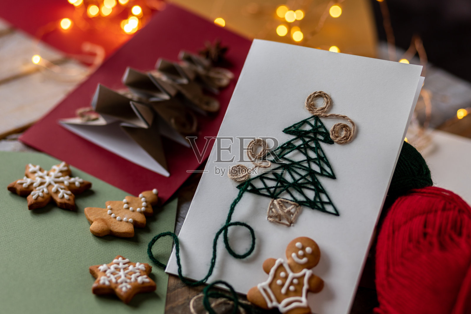 新年或圣诞工艺的概念。由天然可回收材料制成的手工卡片,上面有一棵纸杉树和八角星。干柑橘,姜饼饼干,木制背景照片摄影图片