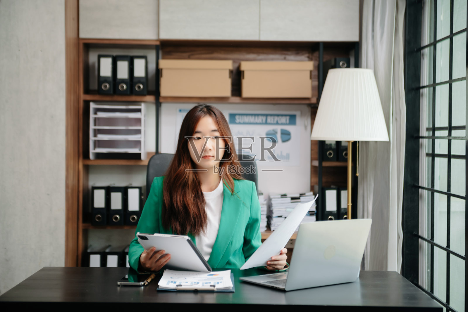 年轻漂亮的女人坐在她的工作场所使用笔记本电脑和平板电脑。专心工作。照片摄影图片