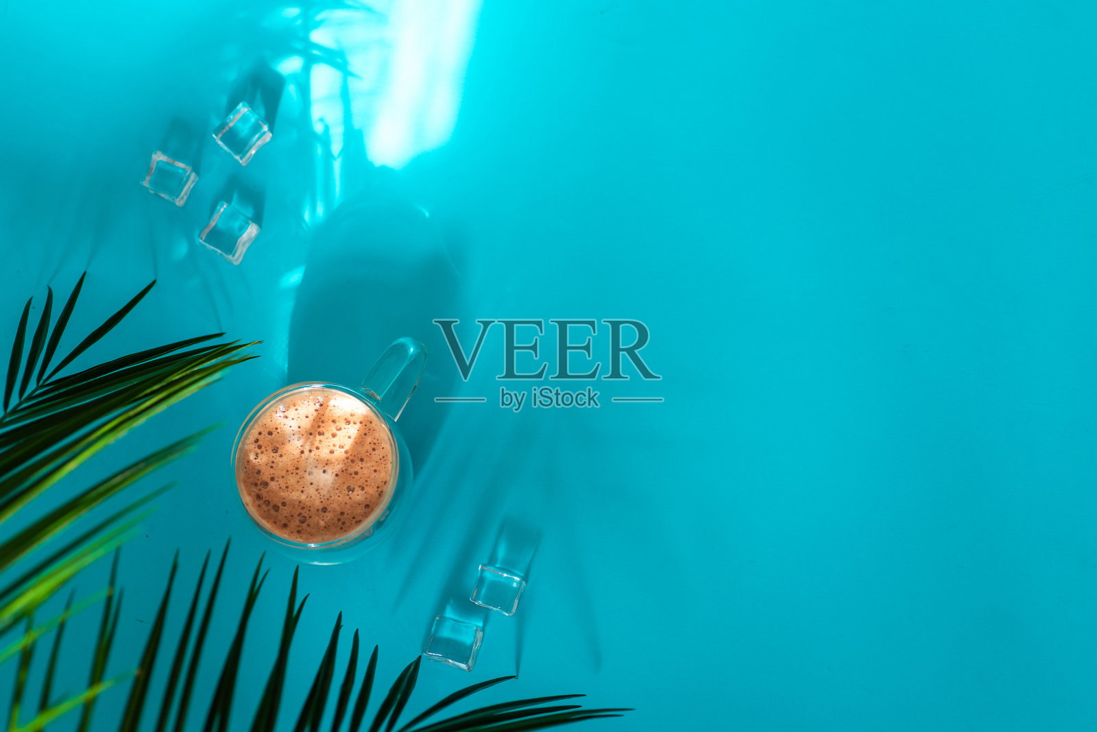 夏季构图-棕榈叶,冰咖啡和冰块在蓝色背景照片摄影图片