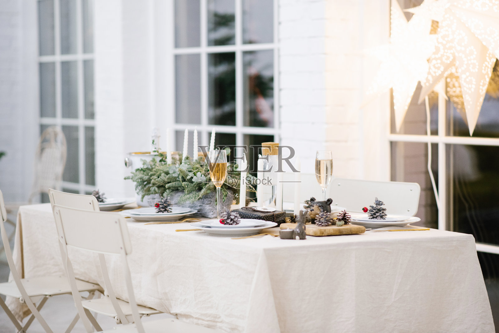 桌子摆得很漂亮,有装饰品、蜡烛和灯笼。客厅里装饰着花环和圣诞树。节日的气氛照片摄影图片