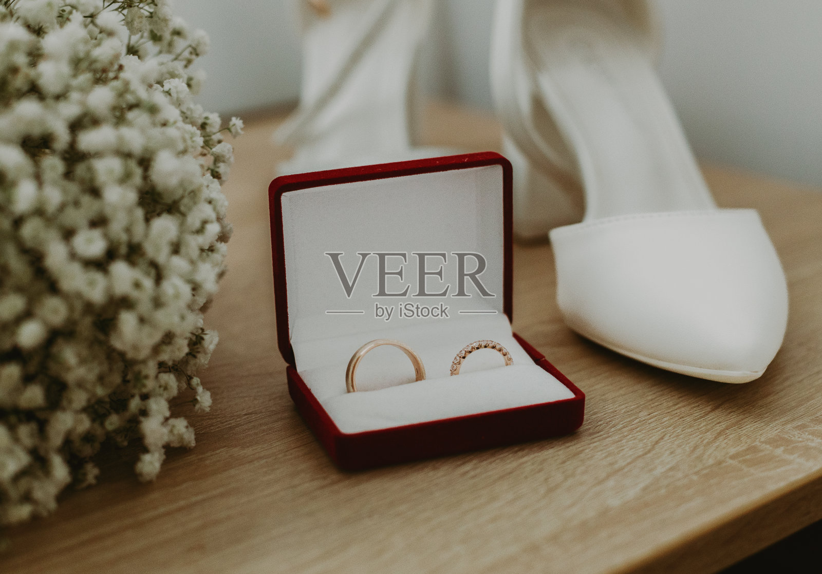 桌子上有结婚戒指、鲜花和鞋子。照片摄影图片