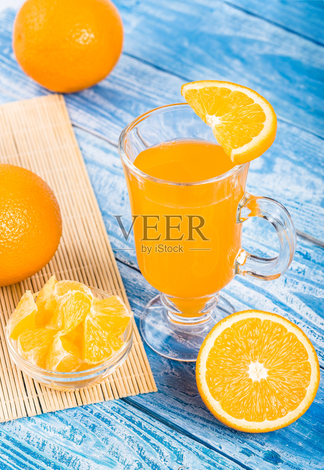 鲜榨柑橘汁。橙色水果和橙汁在一个蓝色的木制背景。放文字的地方。照片摄影图片