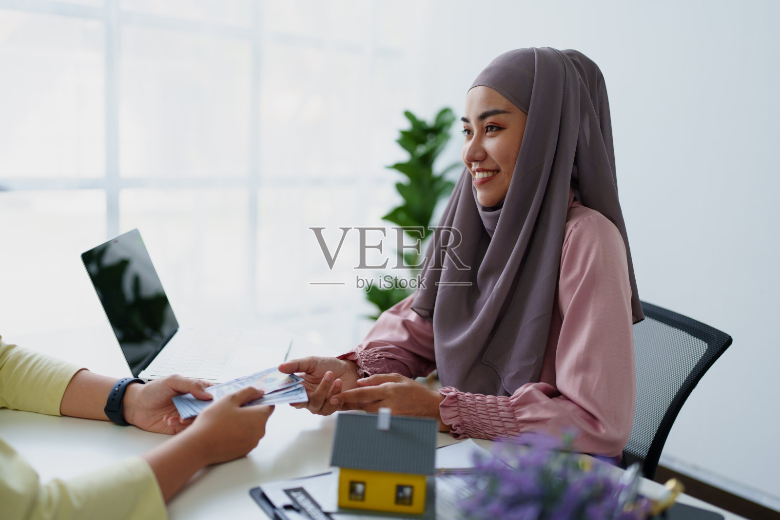 一名穆斯林女银行职员,正在与客户就一笔住宅贷款达成协议。照片摄影图片