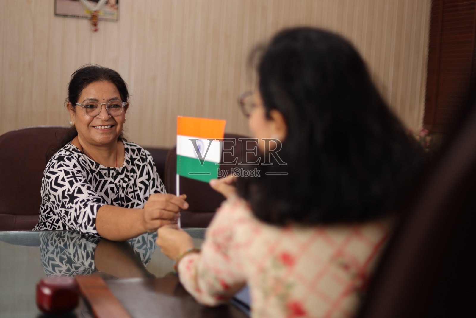 高高在上的镜头,快乐自豪的校长给一位老老师颁发印度国旗作为奖励,因为她在学校服务了很长时间。照片摄影图片