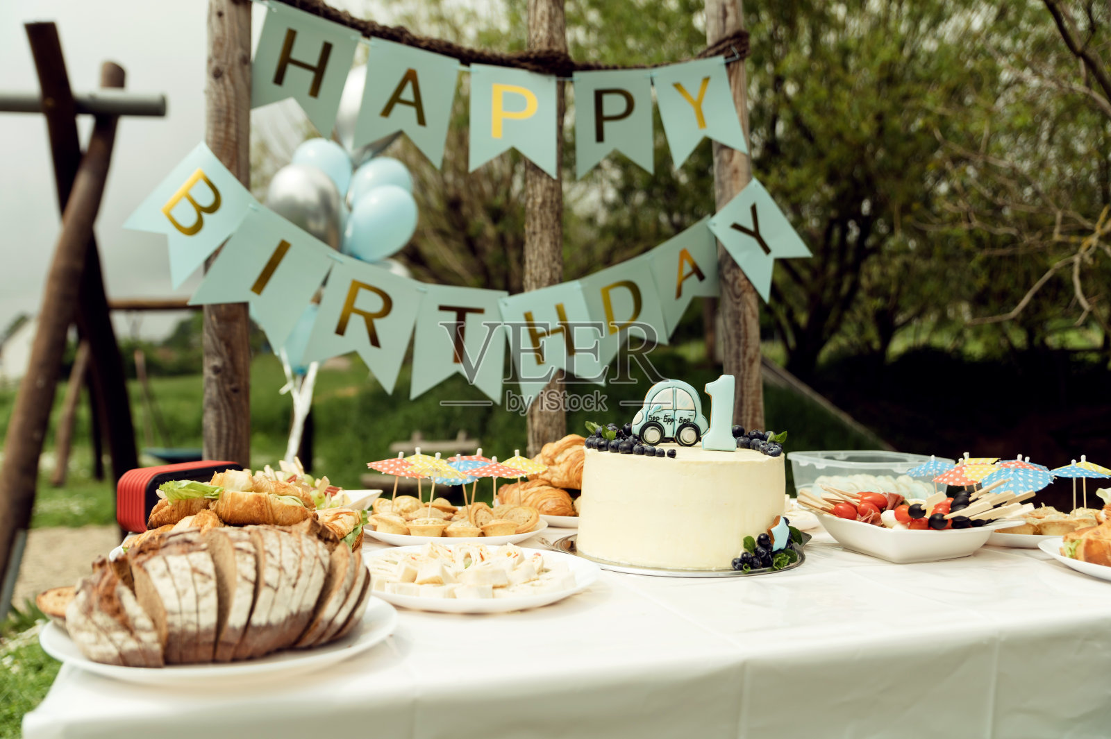第一个生日的宴会。题词,生日快乐。节日餐桌配有食物和小吃,节日餐桌,以乡村风格为理念,在大自然中野餐庆祝生日照片摄影图片