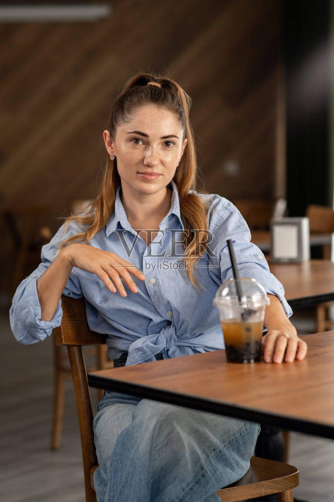 一个年轻女孩在餐馆里拿着一杯珍珠奶茶的照片照片摄影图片