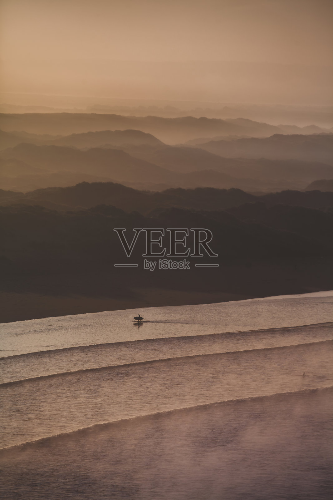 孤独的冲浪者走过喜怒无常的海滩照片摄影图片