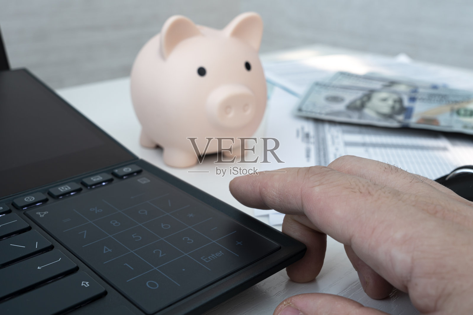 一名男子手持计算器计算费用的特写镜头,桌上放着一个储蓄罐。经济,危机和通货膨胀。成本管理照片摄影图片