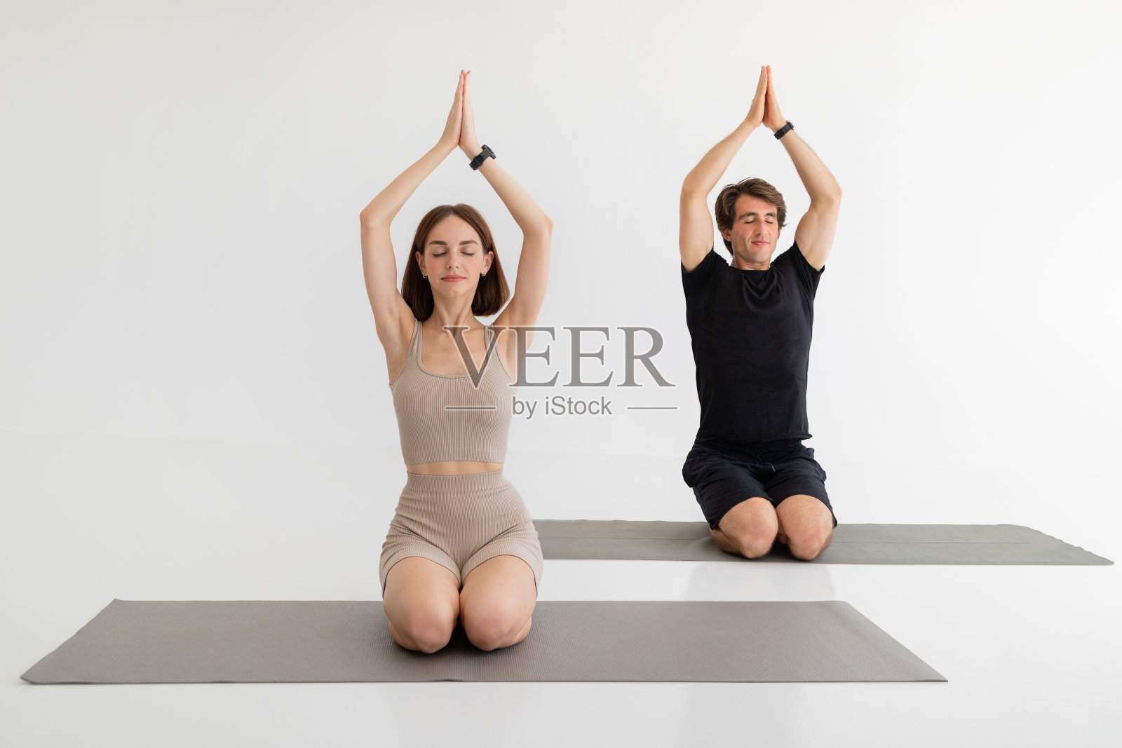 严肃冷静的千禧一代欧洲夫妇穿着运动服坐在地板上练习瑜伽,呼吸练习照片摄影图片