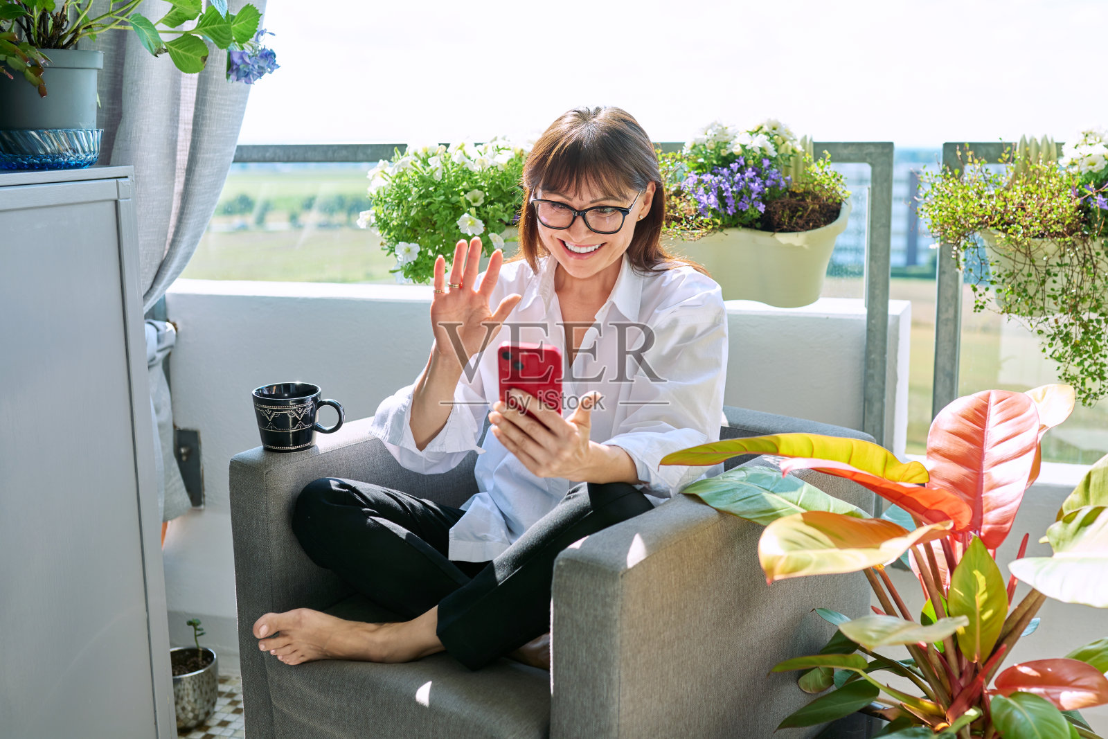 会说话的中年妇女在家里用智能手机打视频电话照片摄影图片