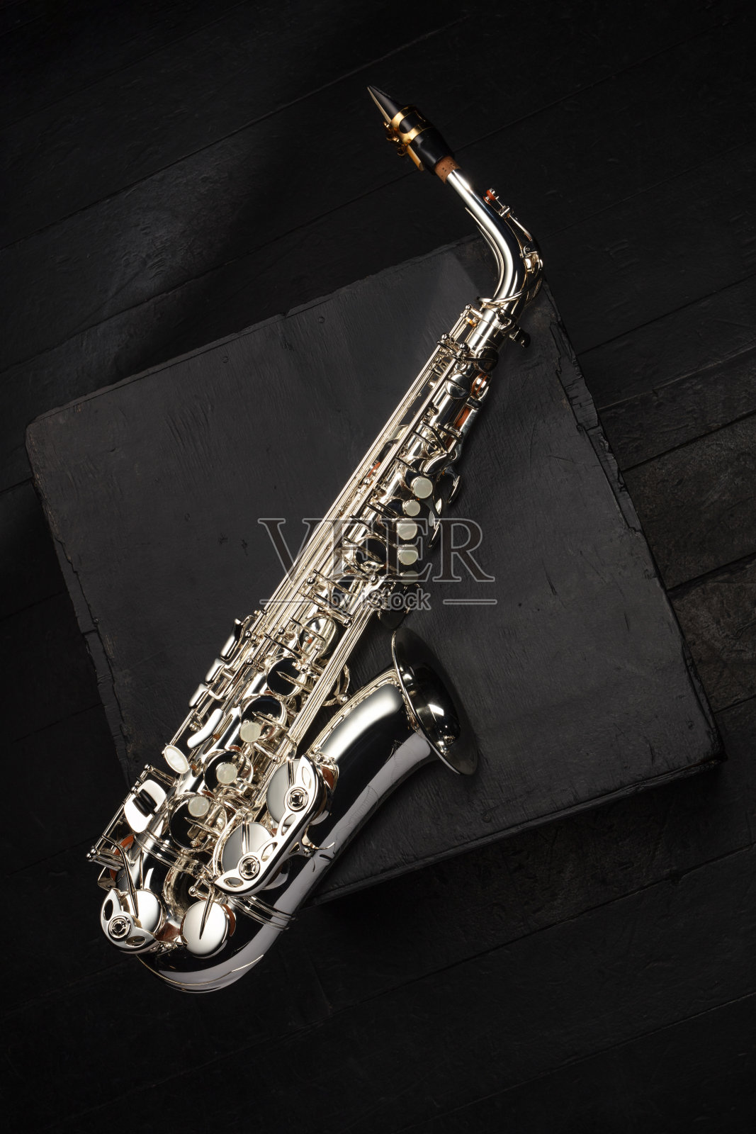 银色萨克斯管放在音乐会舞台黑色地板上破旧的黑色立方体上照片摄影图片