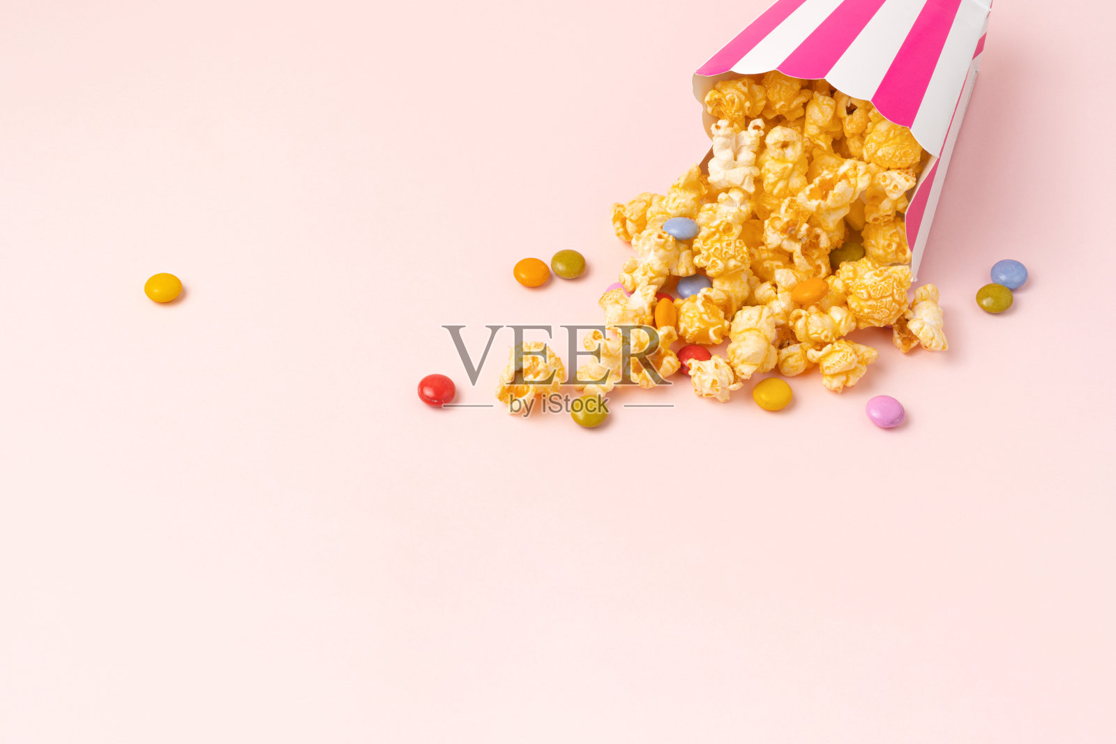 焦糖爆米花和糖果在粉红色的背景。本空间照片摄影图片