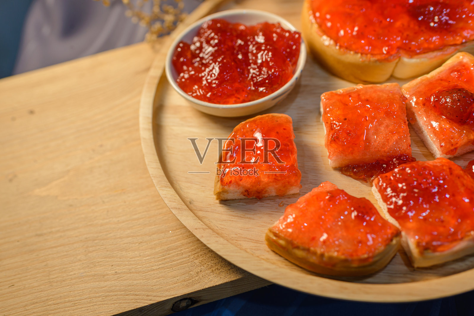 把面包片和草莓酱放在木板上。照片摄影图片