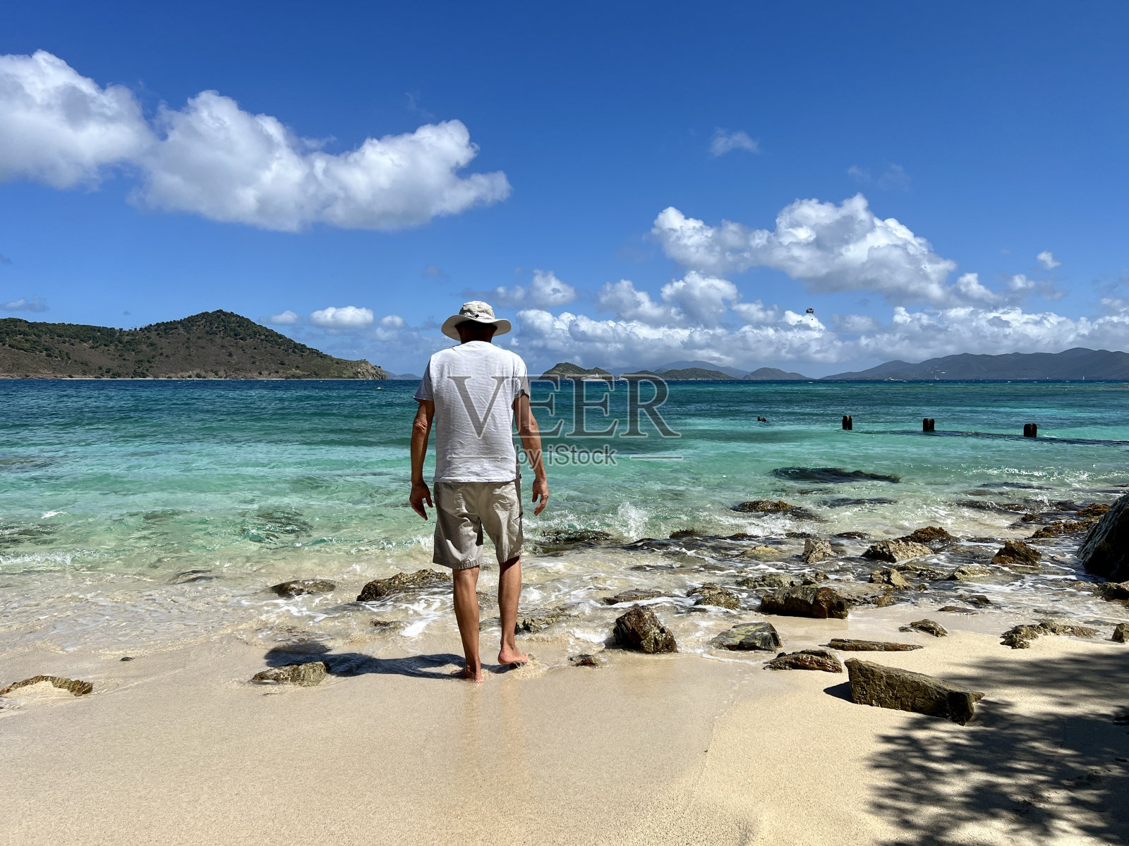 老人的后视图,在清澈的蓝绿色的海水和远处的圣托马斯岛的岛屿上,向水走去照片摄影图片