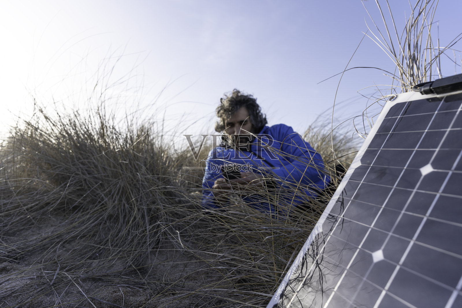 人与自然。一个人在海边拿着手机和太阳能电池板。本空间照片摄影图片