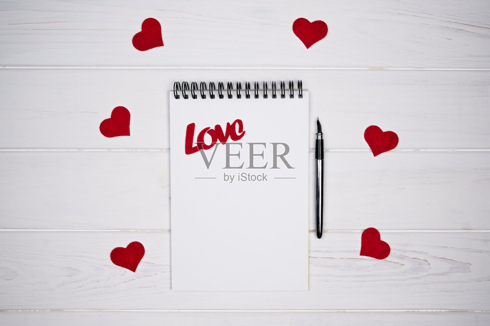 白色木质背景上的笔记本、笔、红色爱心与Love字样照片摄影图片