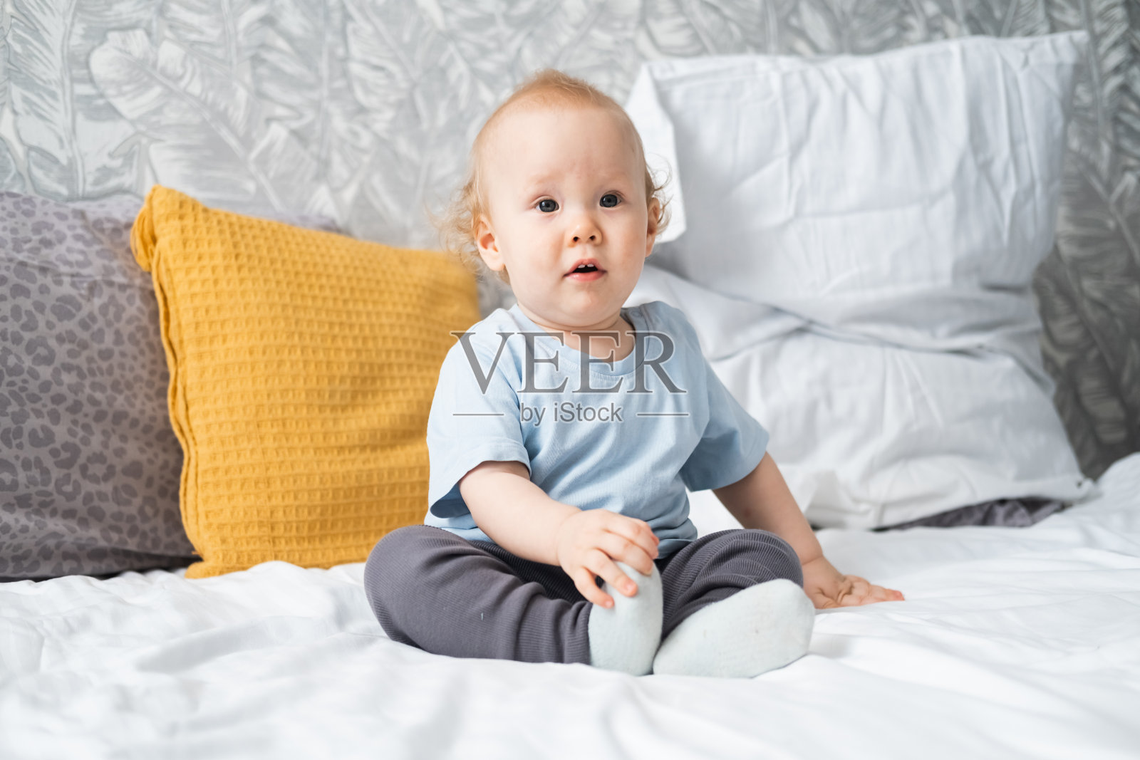 有趣的小男孩坐在床上照片摄影图片