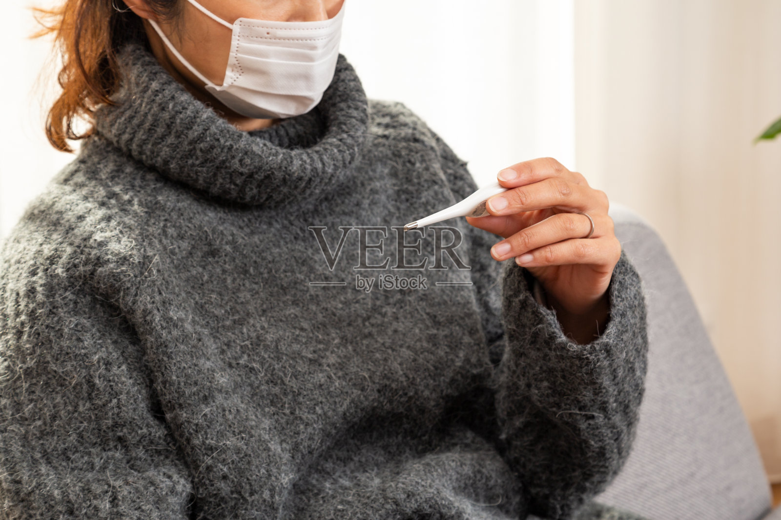 一位女士在客厅里测量体温。照片摄影图片