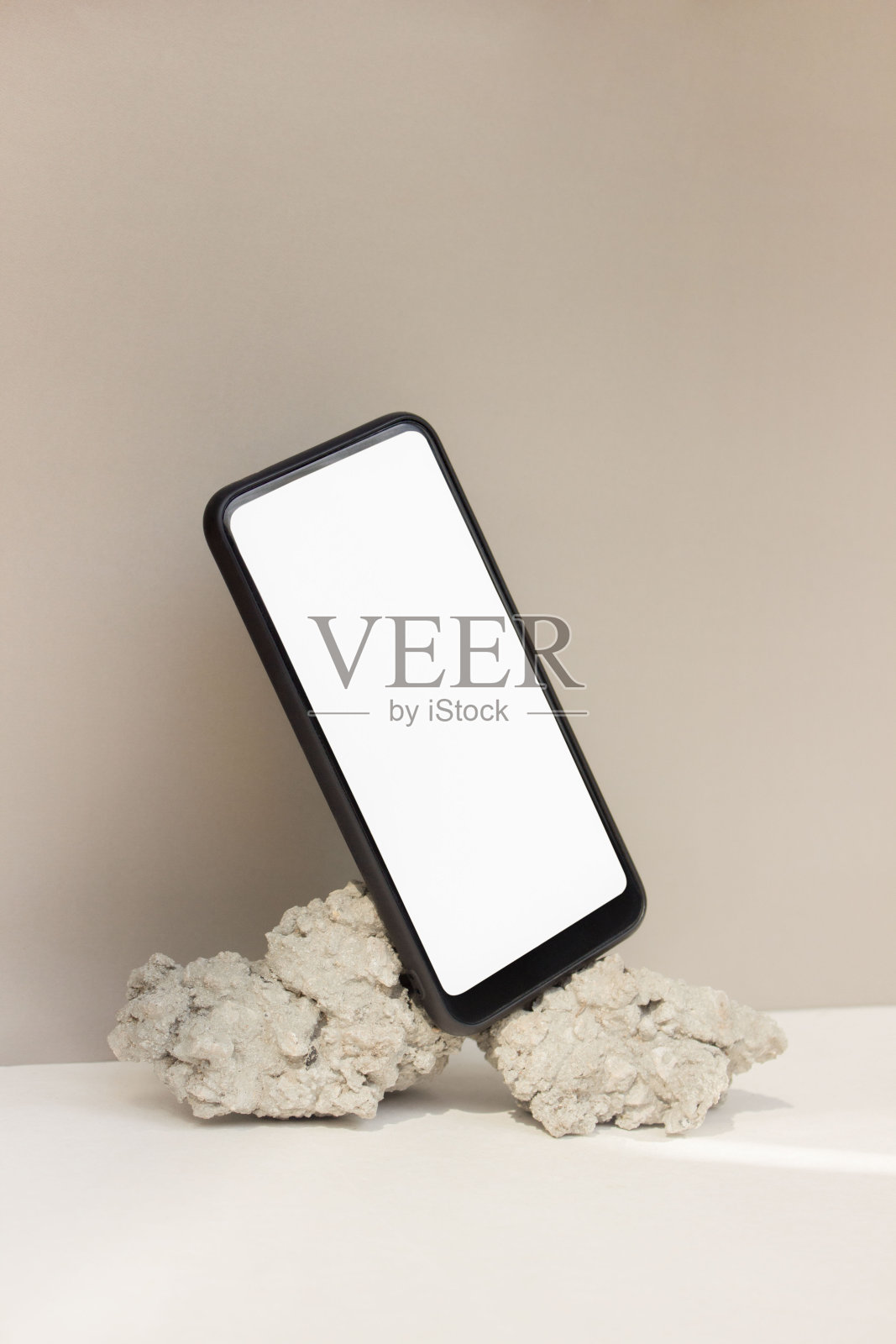 原型模板智能手机平衡在米色背景上的天然石材。手机与空白屏幕模板照片摄影图片