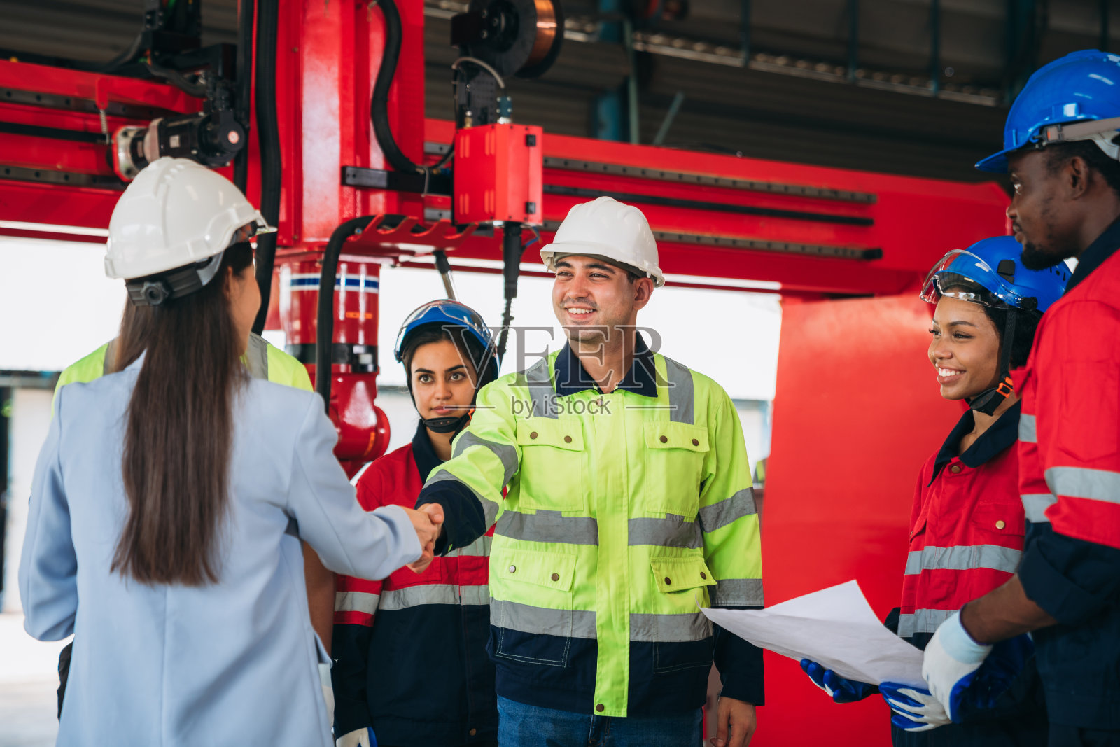 团队工程师和领班手拉手握手,以显示在工厂机器上的成功。工业携手合作。照片摄影图片