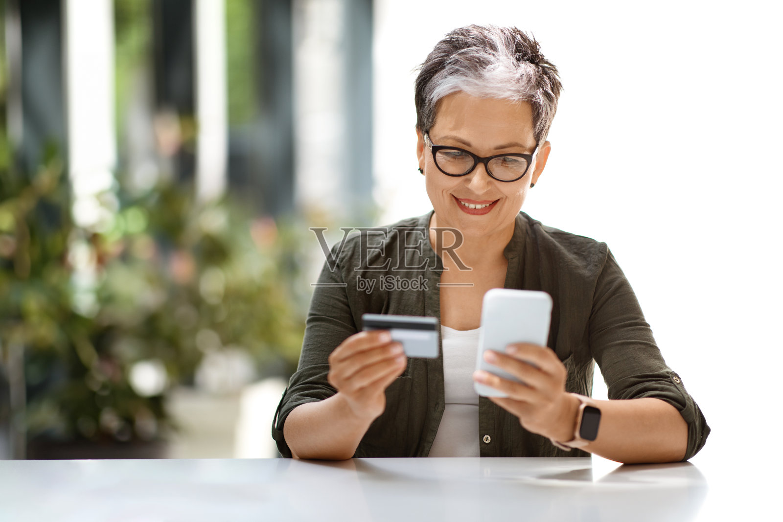 开朗迷人的成熟女性,使用银行卡和电话照片摄影图片