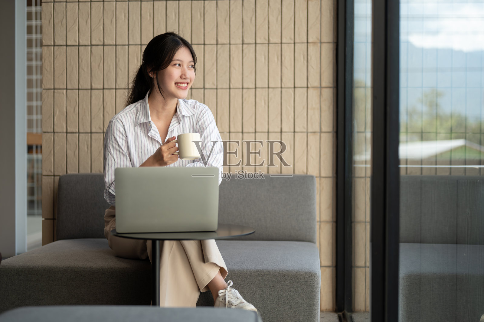 一位充满灵感的亚洲女商人在一家咖啡馆远程办公,一边喝着咖啡,一边做白日梦。照片摄影图片