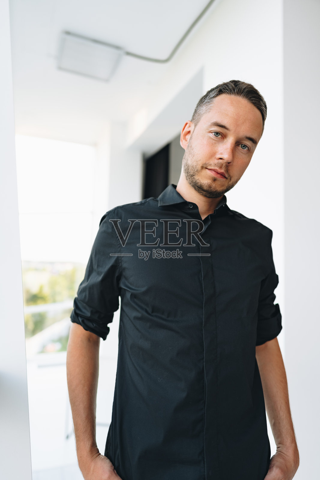 一个穿着黑衬衫的男人在照相馆摆姿势的肖像照片摄影图片