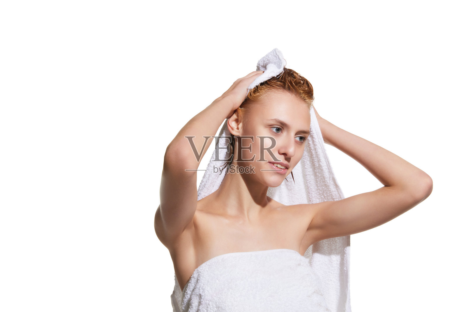 沐浴后的女孩站在毛巾上,头发湿漉漉的,背景是白色的摄影棚。用毛巾擦干头发照片摄影图片