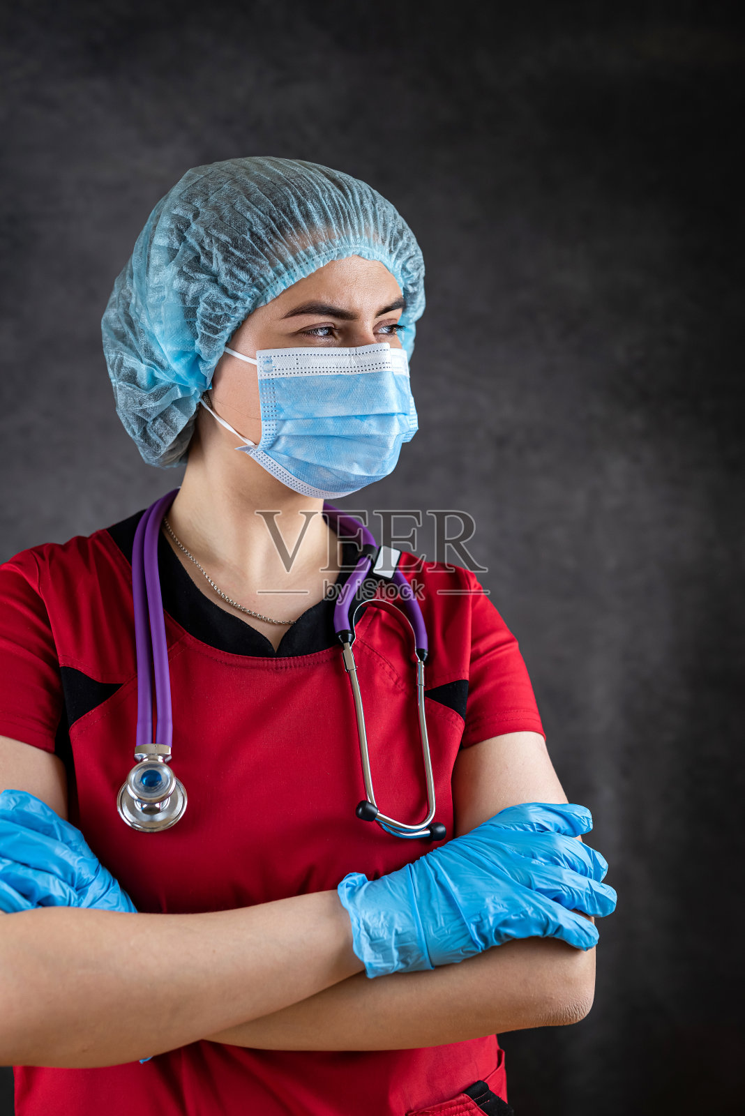 年轻的白人女医生护士穿着红色制服,戴着口罩和橡胶手套,戴着听诊器照片摄影图片