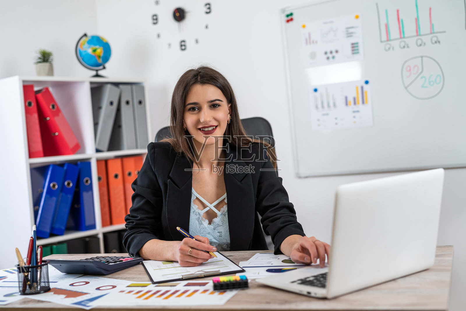 单身微笑的商务女性穿着西装在办公室拿着纸质图表文件工作照片摄影图片