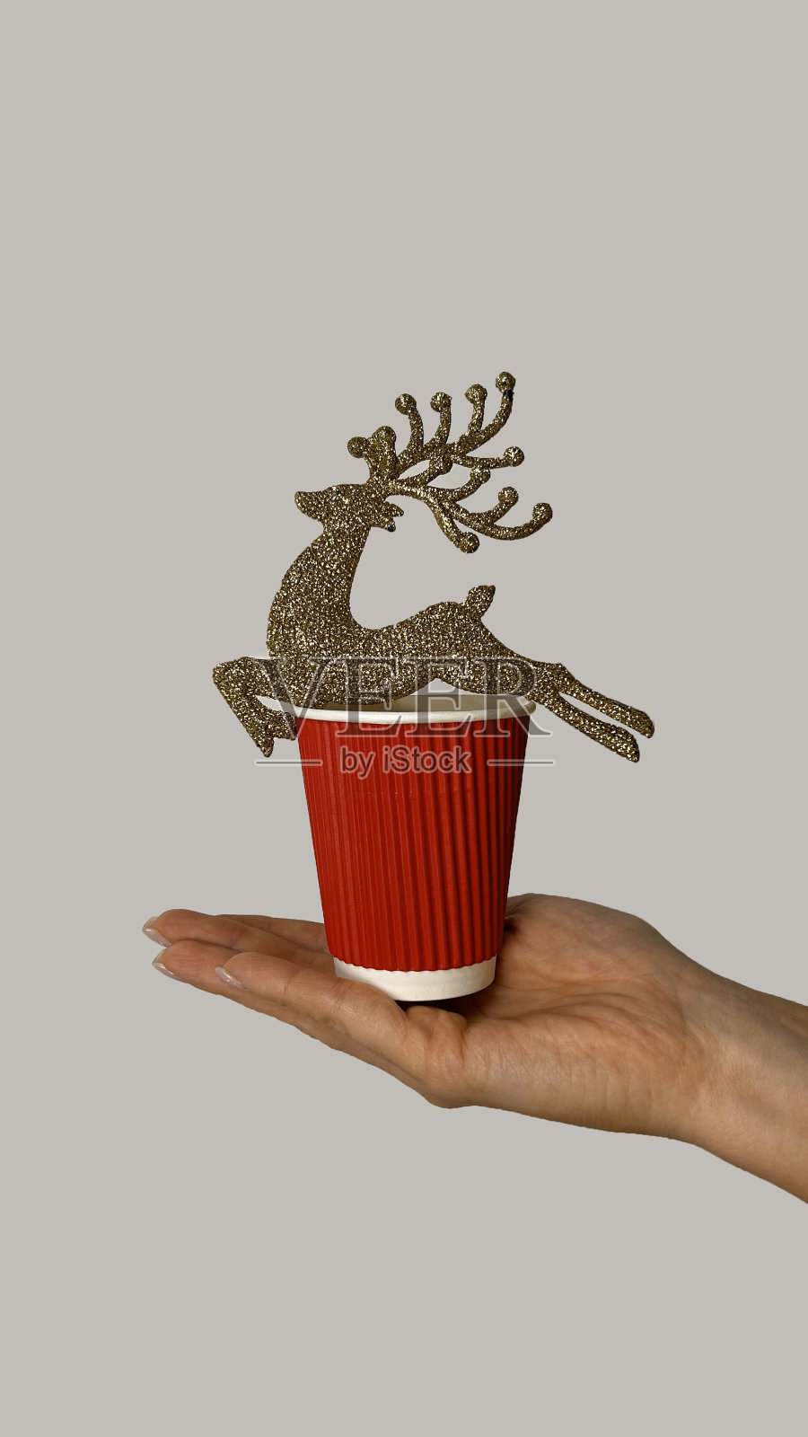 一个戴着圣诞金鹿的女人手里拿着一个红纸杯。圣诞节。新的一年照片摄影图片