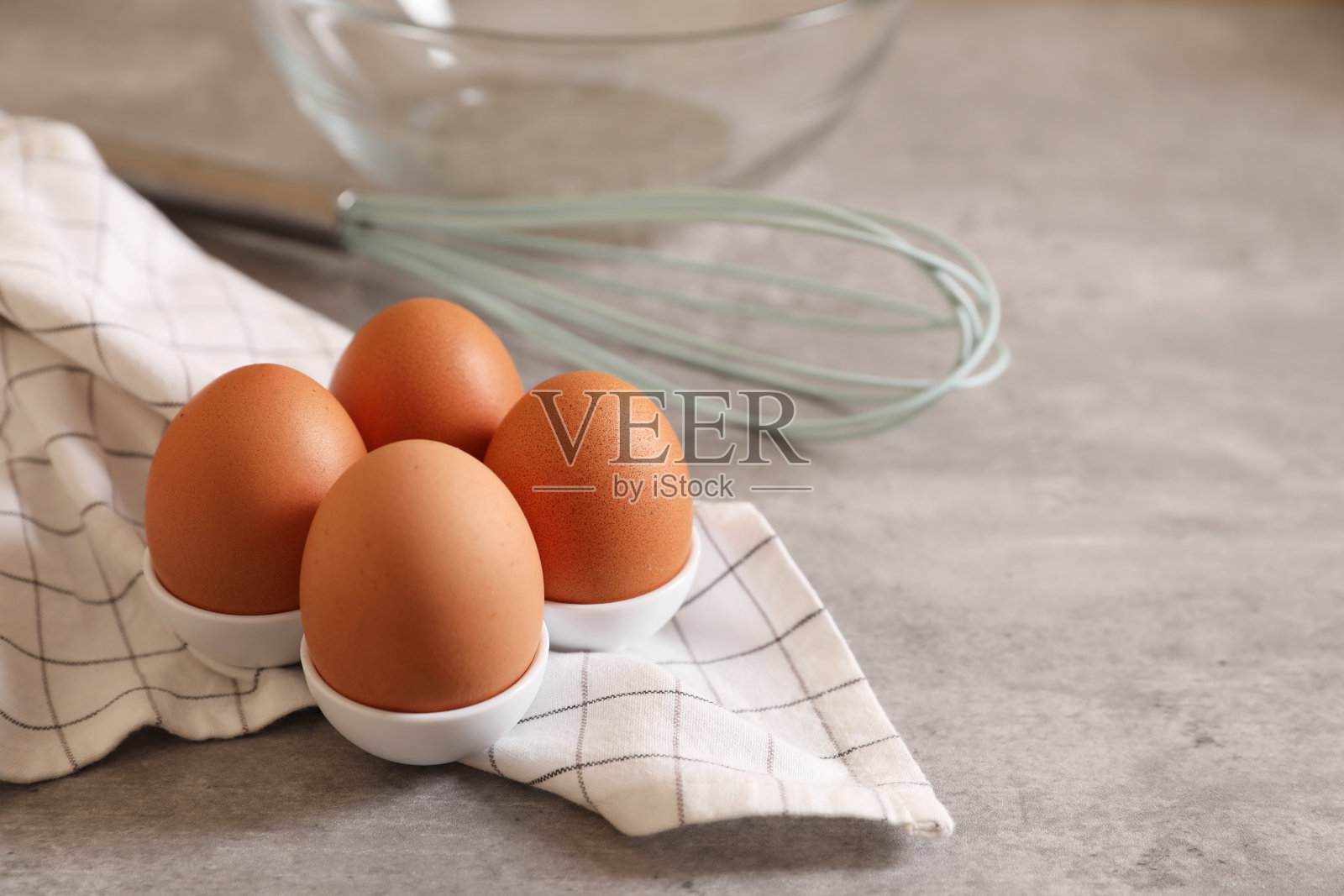 鸡蛋、打蛋器、玻璃碗和餐巾放在灰色的桌子上,留给文字的空间照片摄影图片