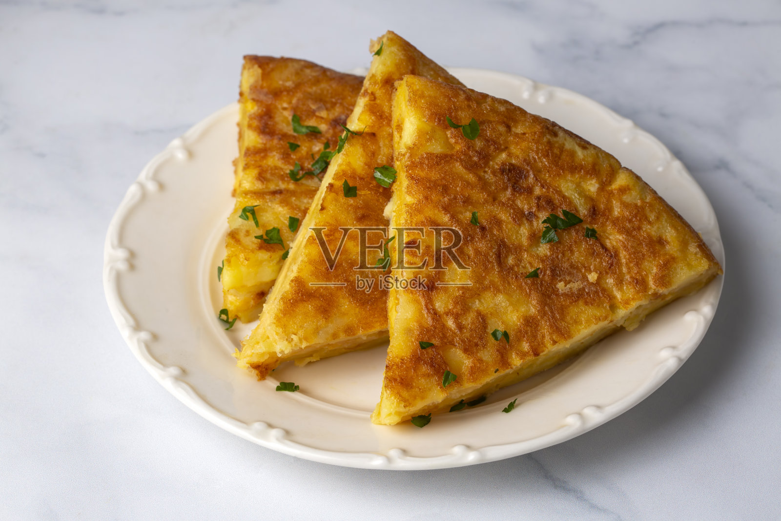 西班牙煎蛋配土豆,典型的西班牙菜,铺在灰色的混凝土地板上。玉米粉圆饼诺拉。土耳其的名字;Yumurtali patates照片摄影图片