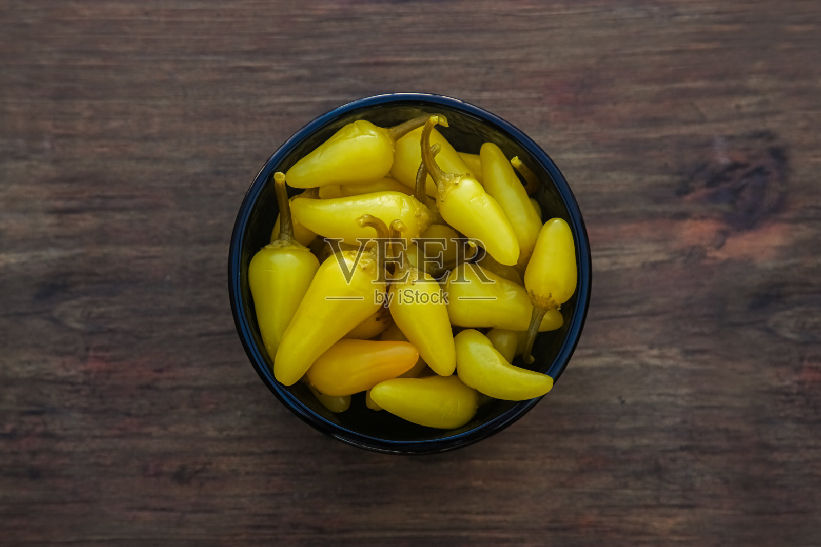 木桌上一碗腌制的黄色墨西哥胡椒,俯视图照片摄影图片