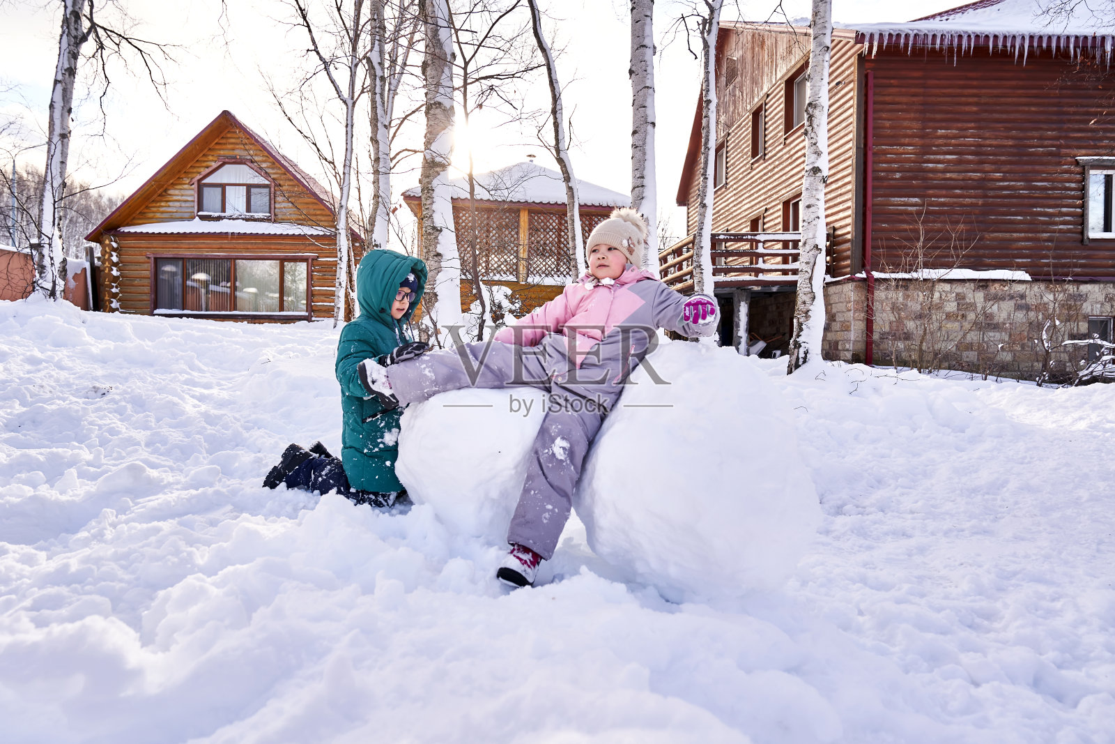冬天,一家人在院子里用白雪堆雪人。照片摄影图片
