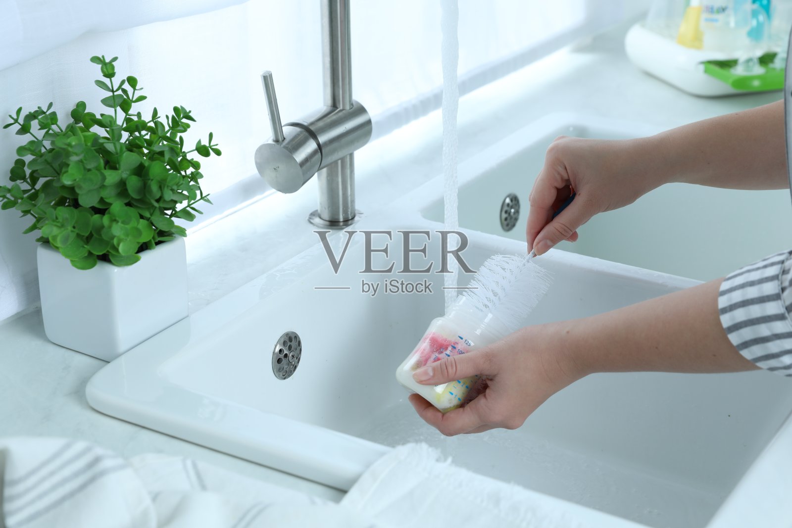 妇女在厨房洗奶瓶,特写照片摄影图片