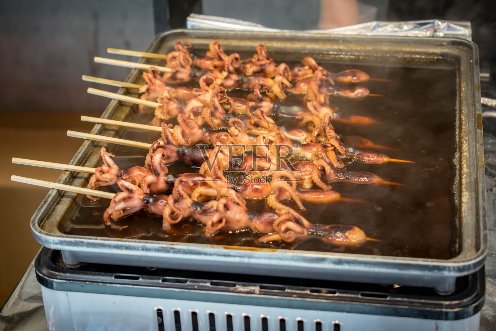 日本东京筑地外市场或筑地鱼市场的正宗街头小吃:章鱼串作为小吃。照片摄影图片