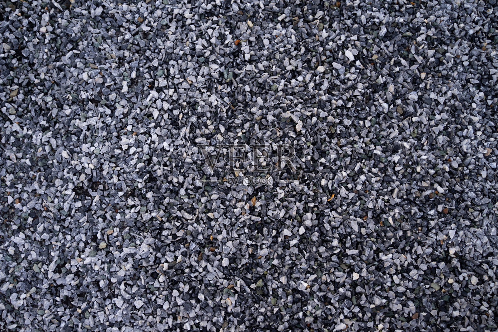 小卵石石背景,深色湿砾石和灰色干砾石。黑色小路照片摄影图片
