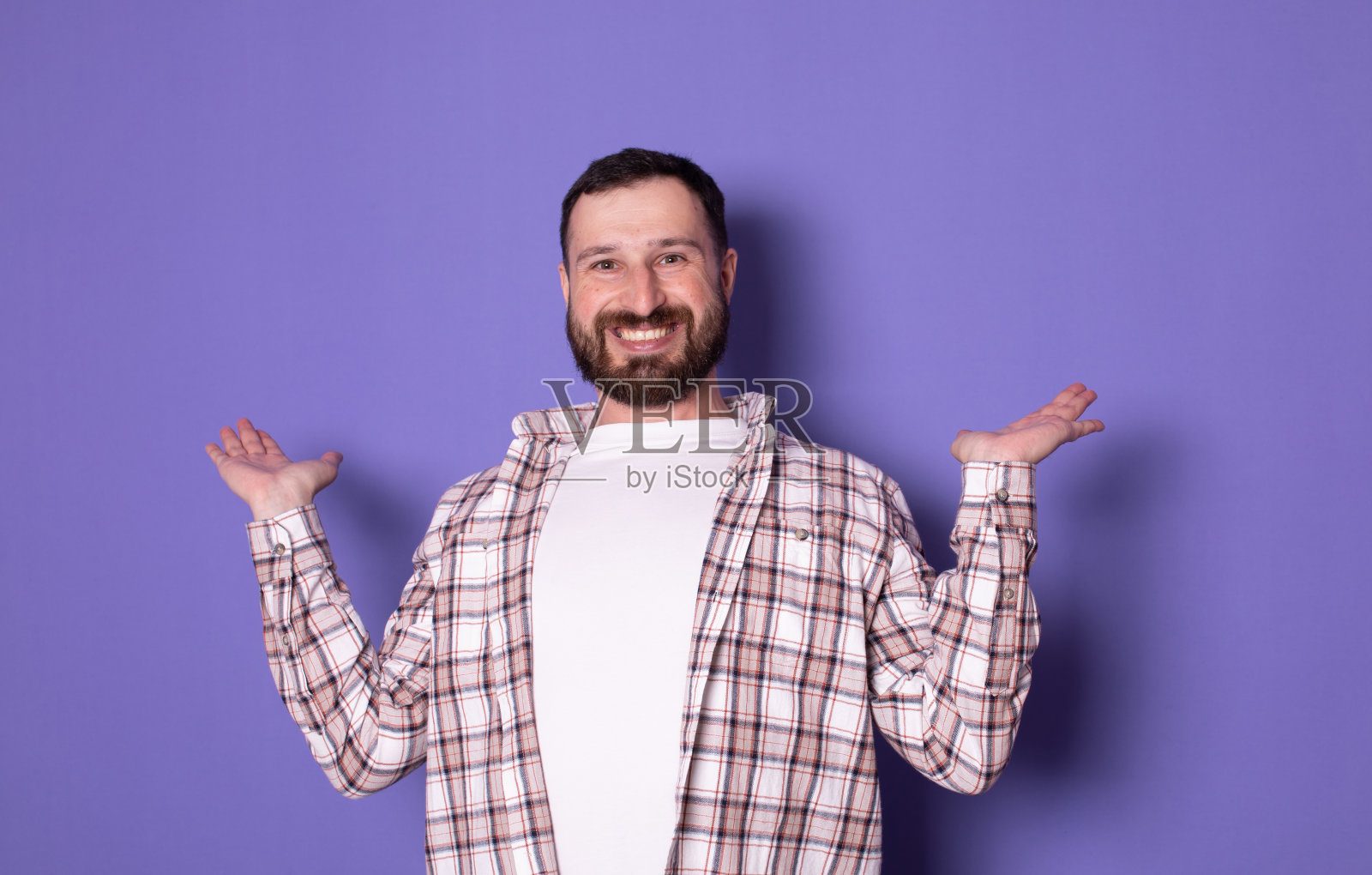 乐观的留着胡子的年轻人手里拿着看不见的东西。照片摄影图片