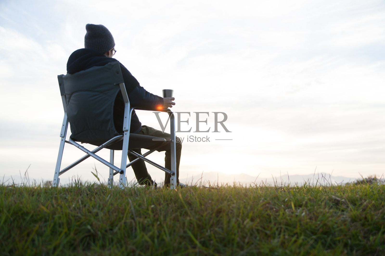 一个男人坐在椅子上,一边喝着咖啡,一边看日出照片摄影图片